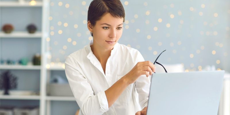 Successful young business woman working on laptop computer in home office, responding to emails, visiting company website, developing online store, making order or studying new personal growth courses