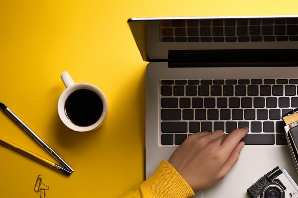 gult billede laptop kamere og en arm der taster